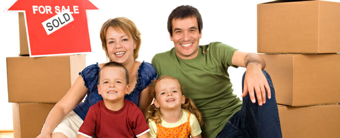 Happy family on the floor with cardboard boxes moving in their new home